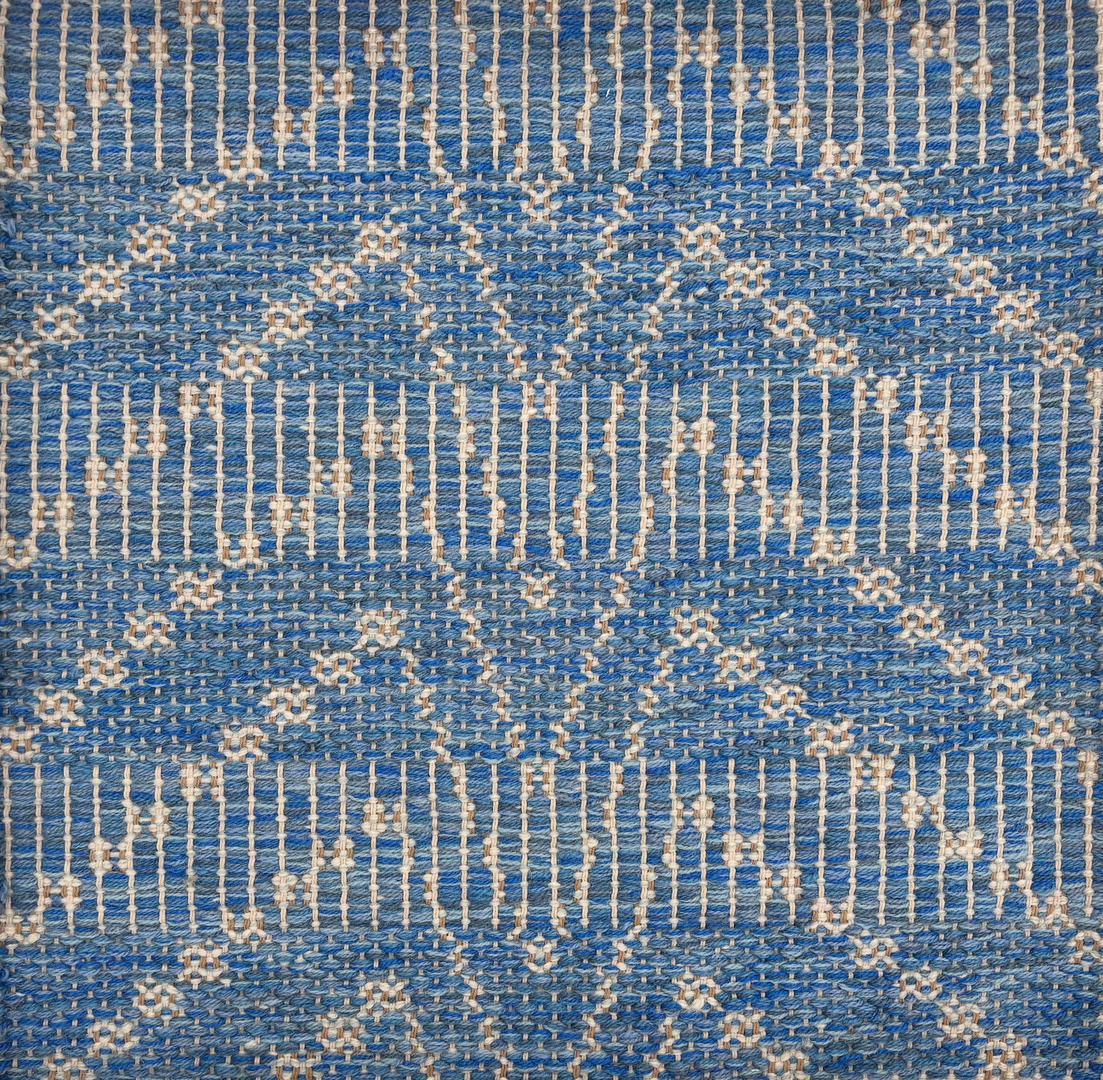 Handwoven rug sample in a bold chevron pattern in marine blue with white striping. 