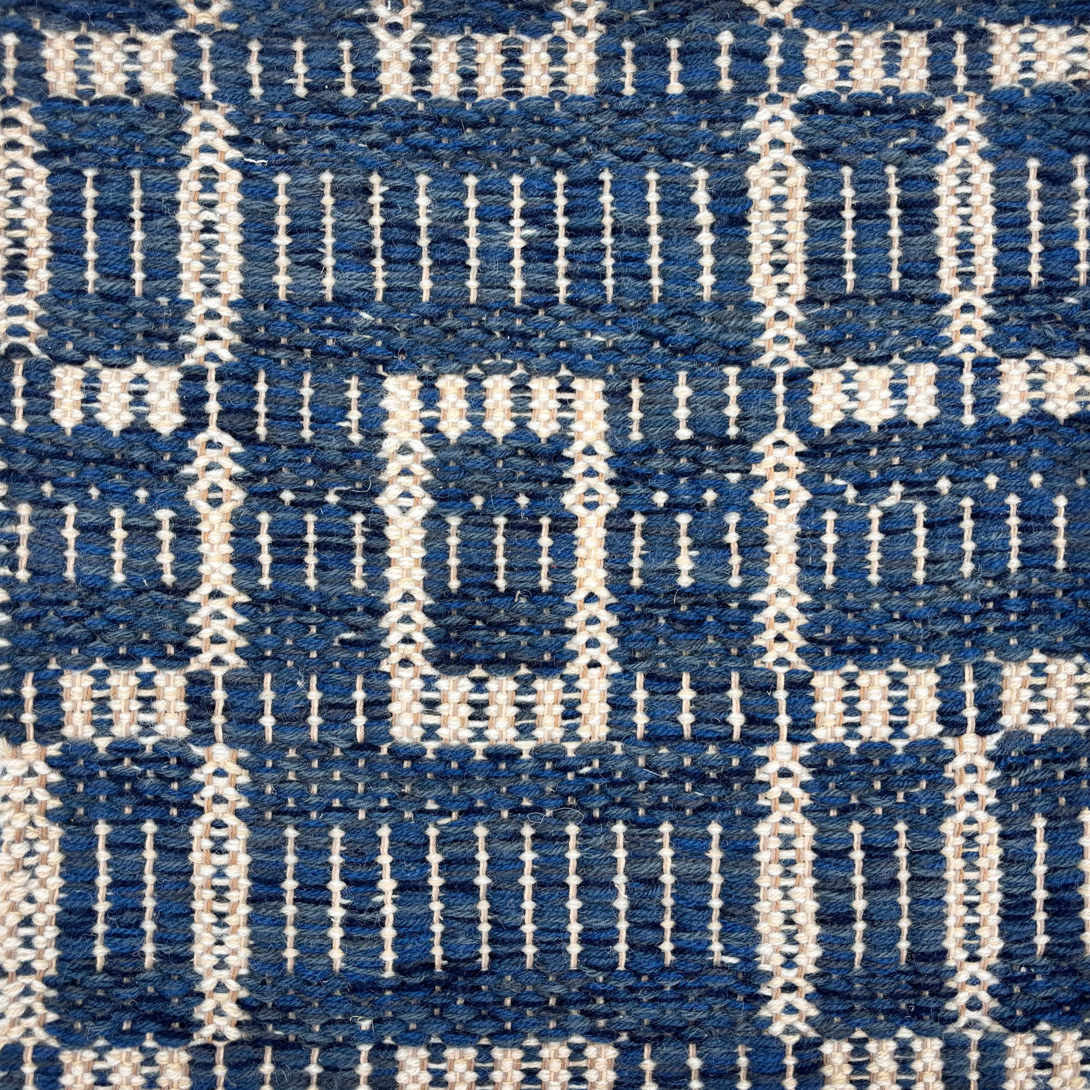 Handwoven rug sampe in with a deep blue field with a gridded square motif in ivory. 