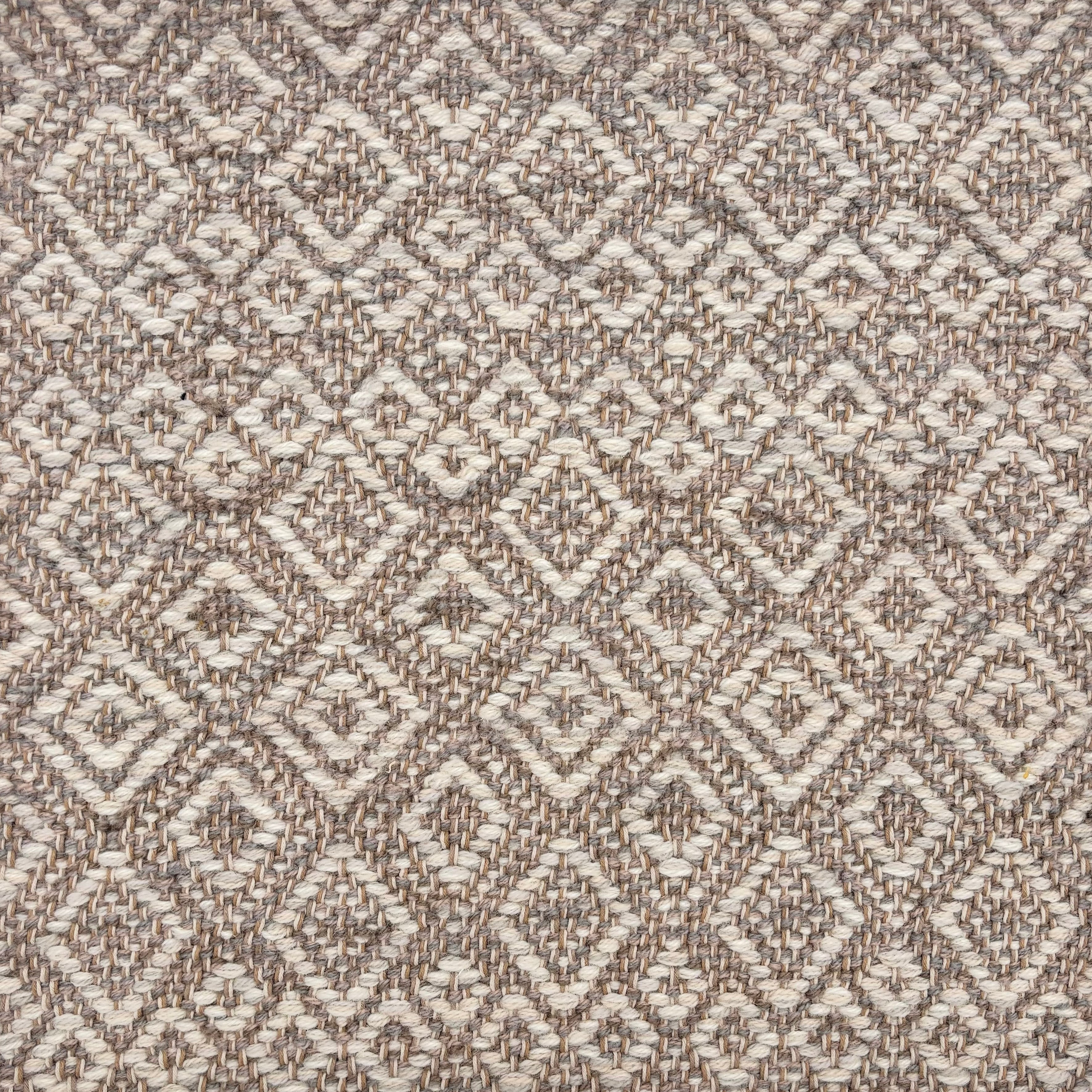 Handwoven rug sample in a radiating diamond pattern in shades of taupe and cream. 