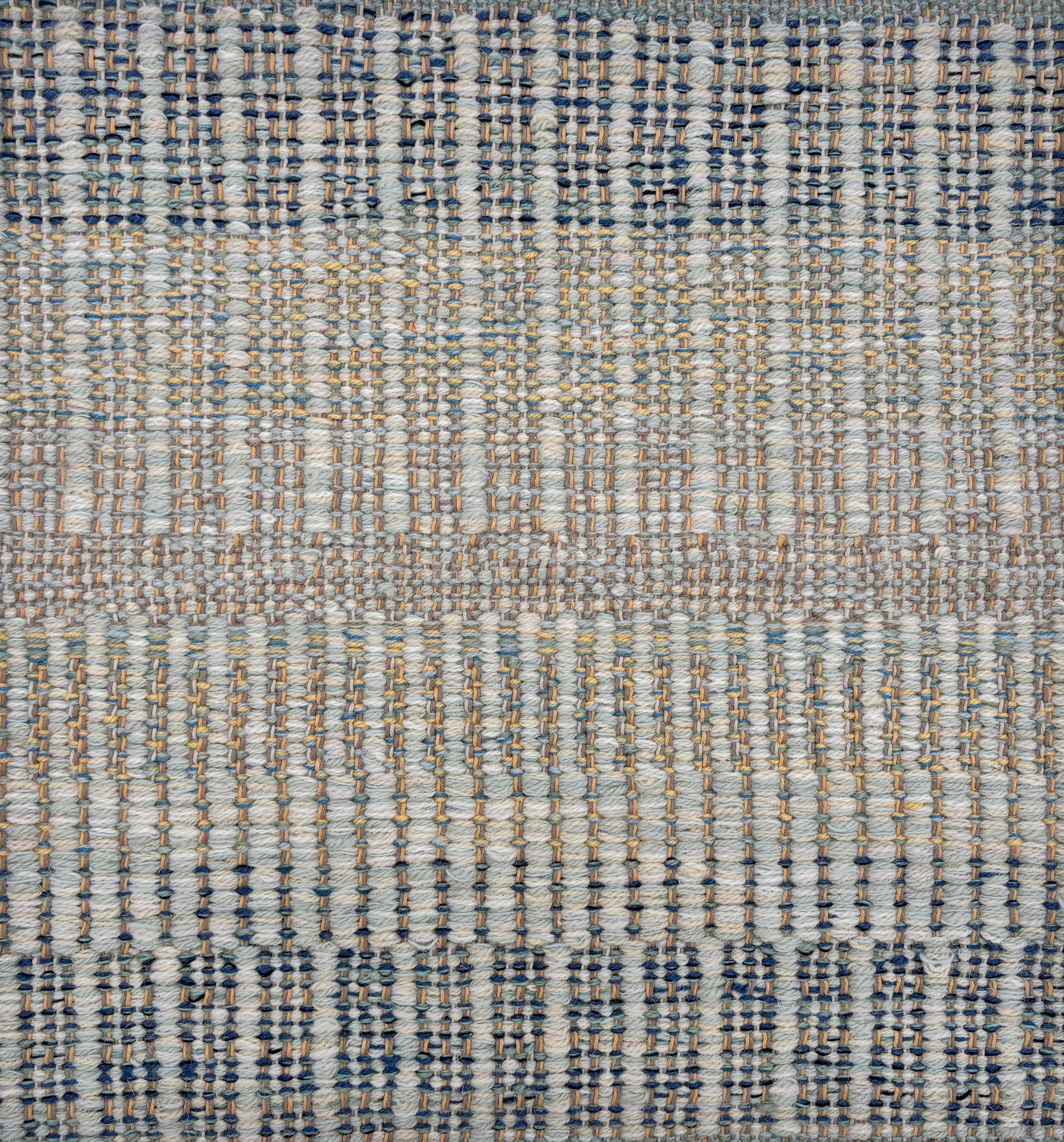 Handwoven rug sample in a textural stripe design in mottled shades blue, grey, tan and yellow. 