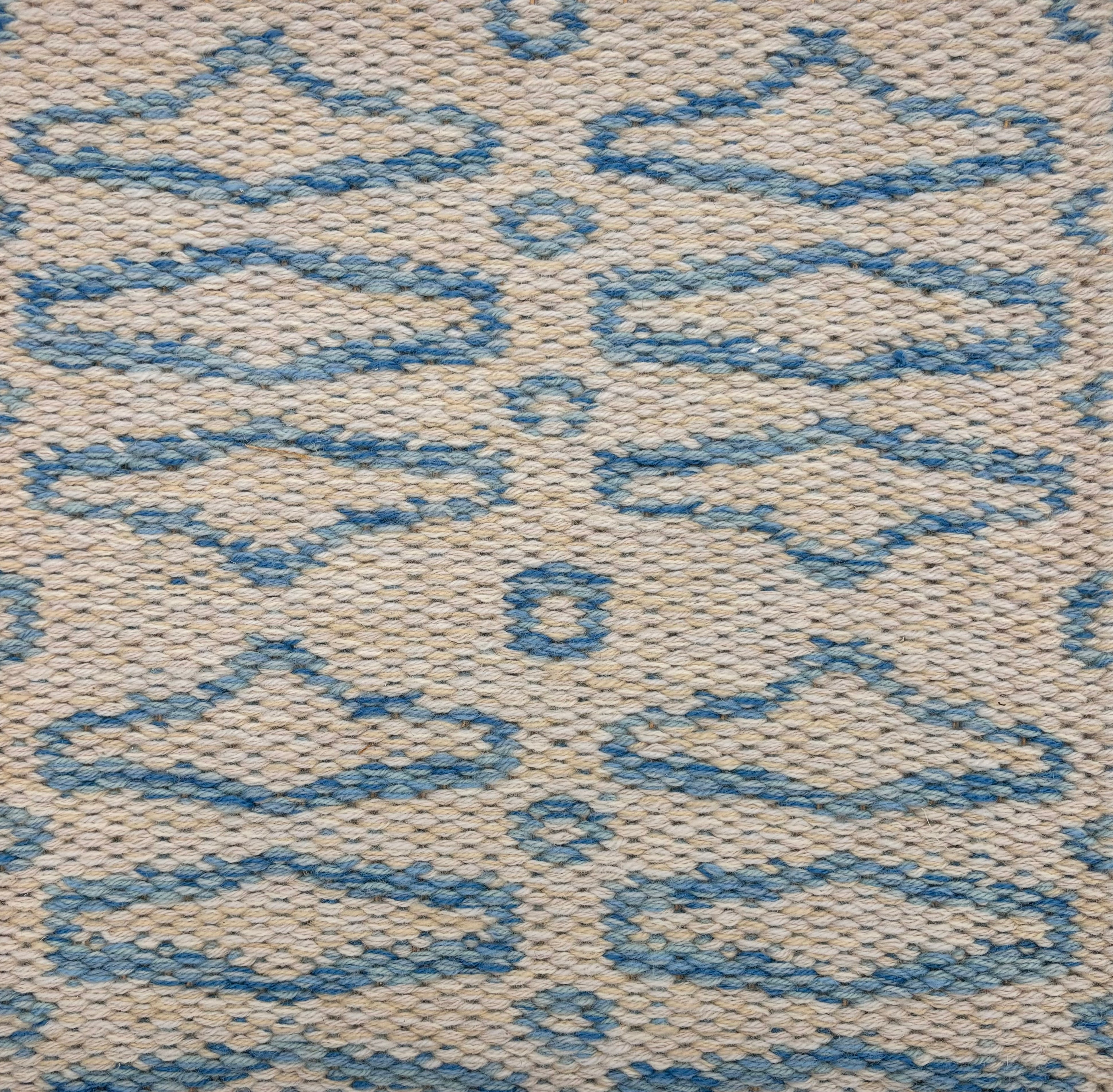 Handowoven rug sample with an abstract geometric linear design in marine blue on a cream field. 