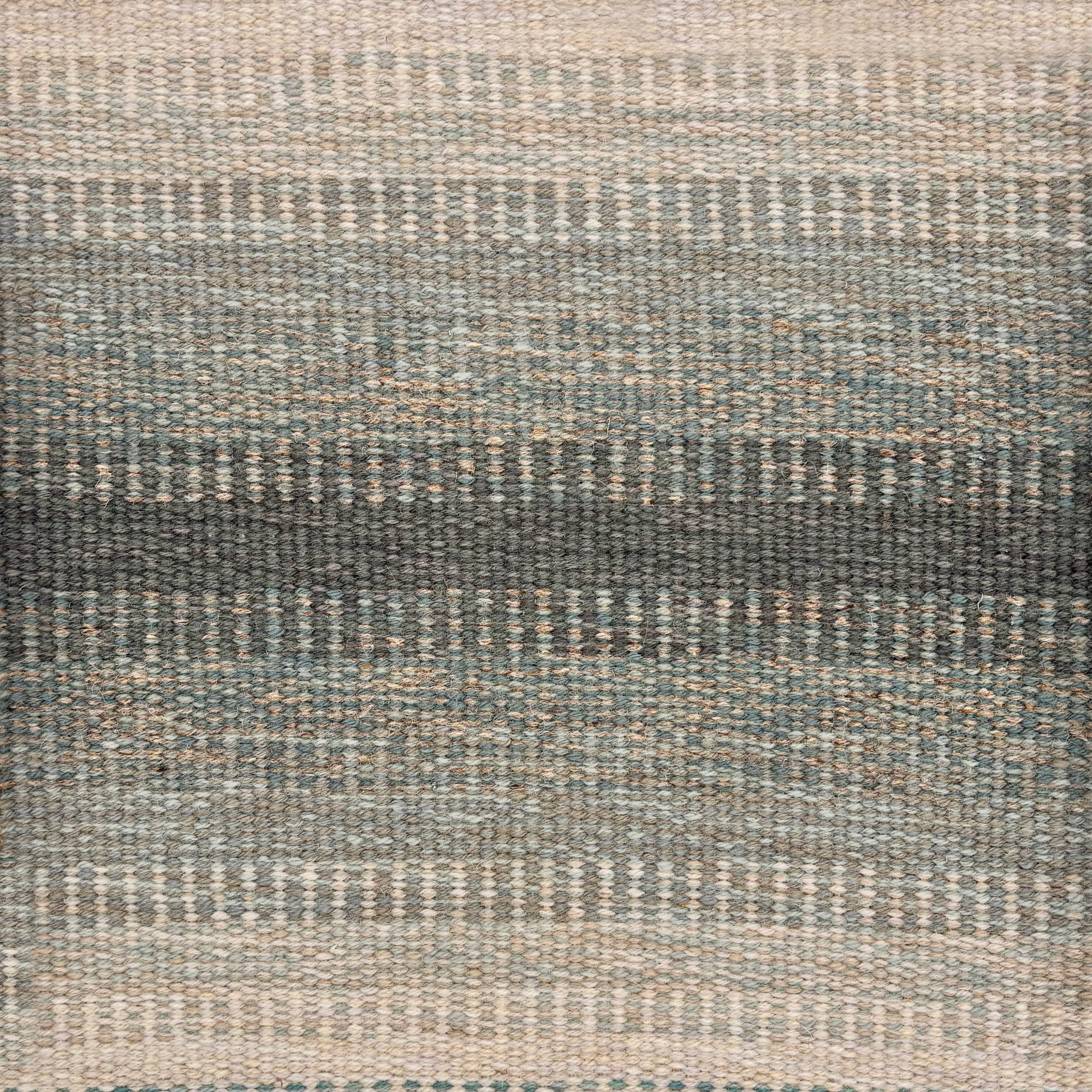 Handwoven rug sample in a subtle striped ombré pattern ranging from beige to sea green. 