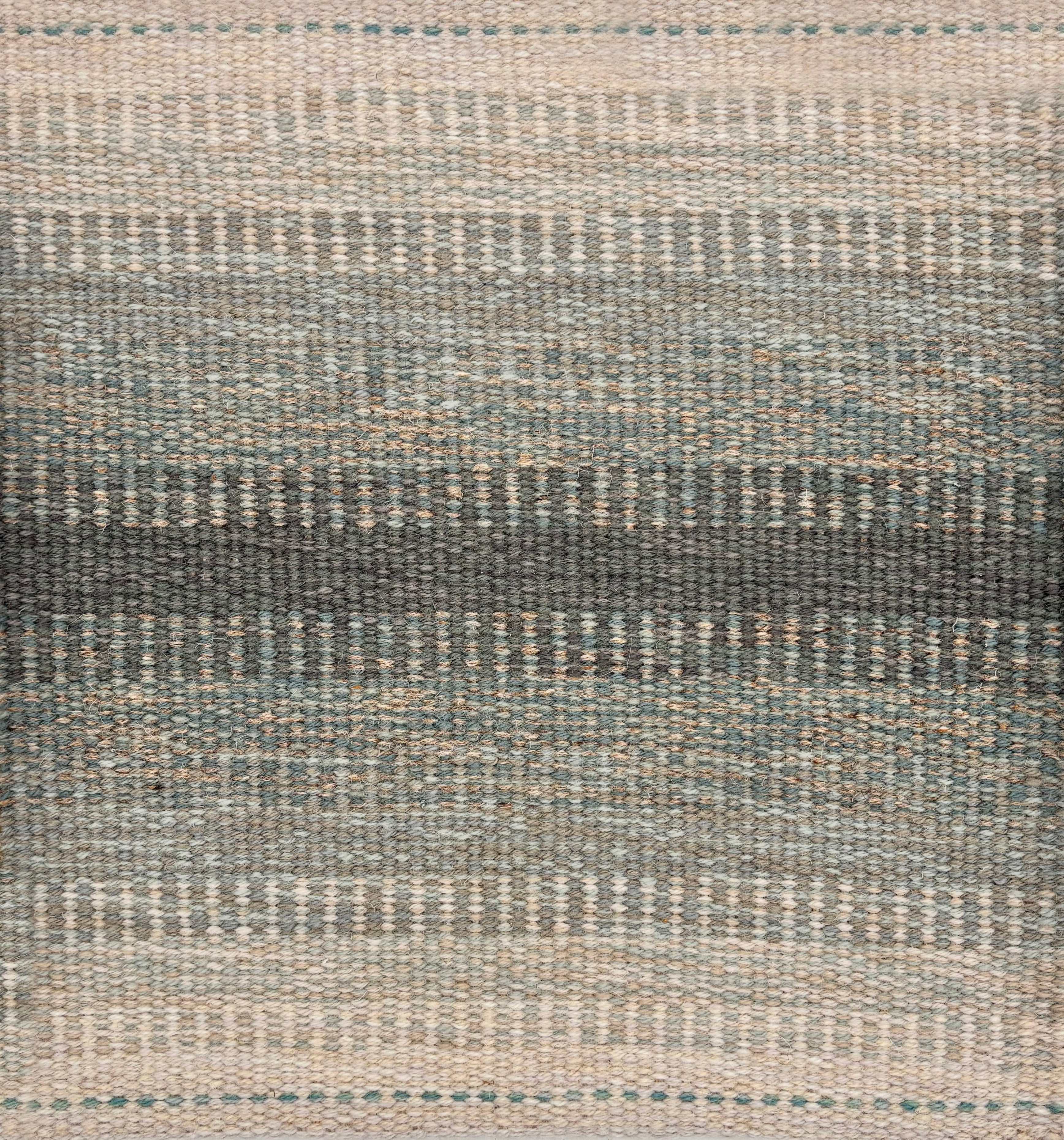 Handwoven rug sample in a subtle striped ombré pattern ranging from beige to sea green. 