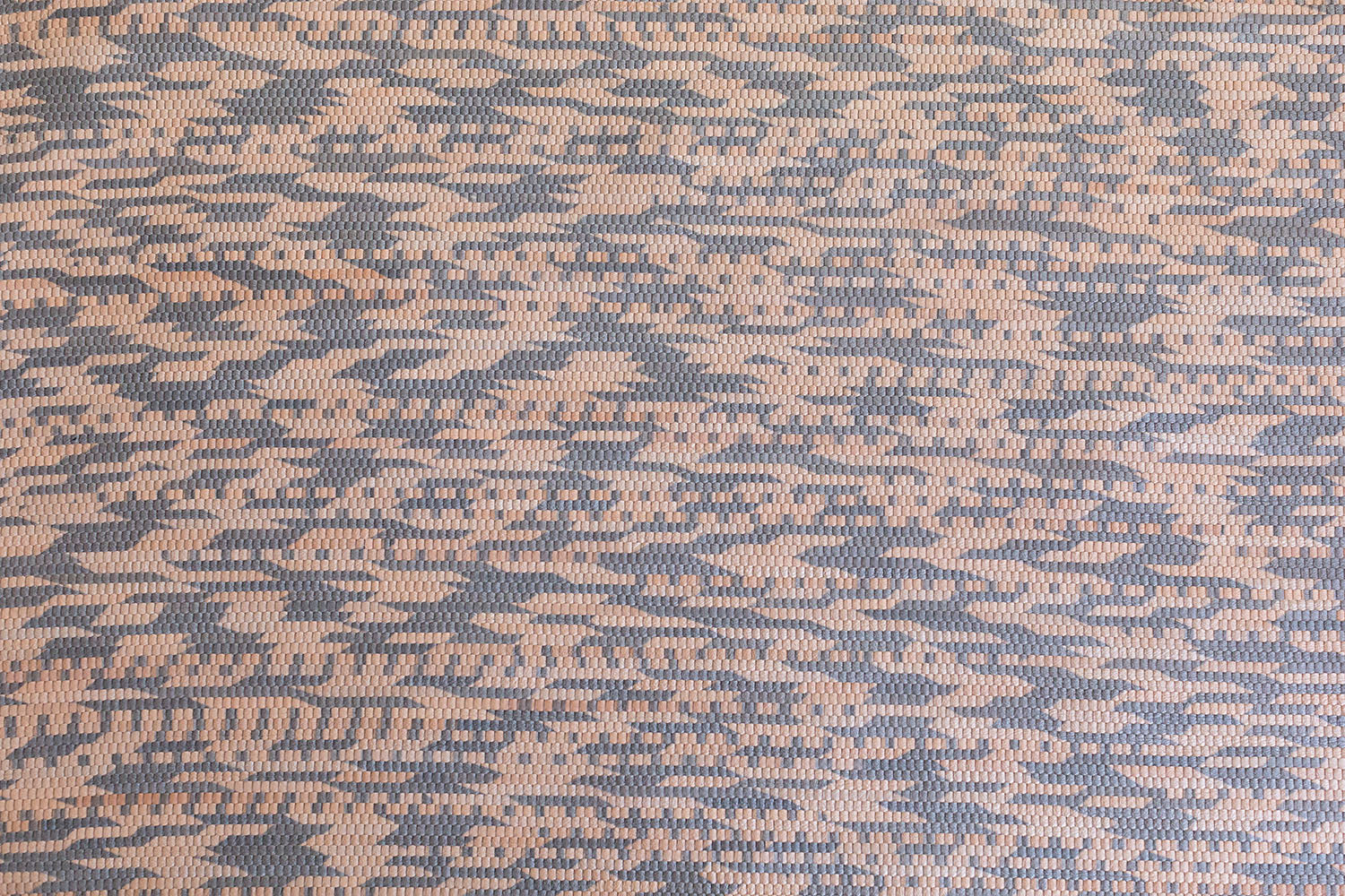 Detail of handwoven leather in a graphic geometric pattern in tan and grey.