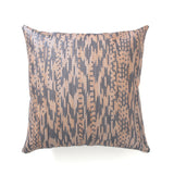 A pillow made with handwoven leather in a graphic geometric pattern in tan and grey.