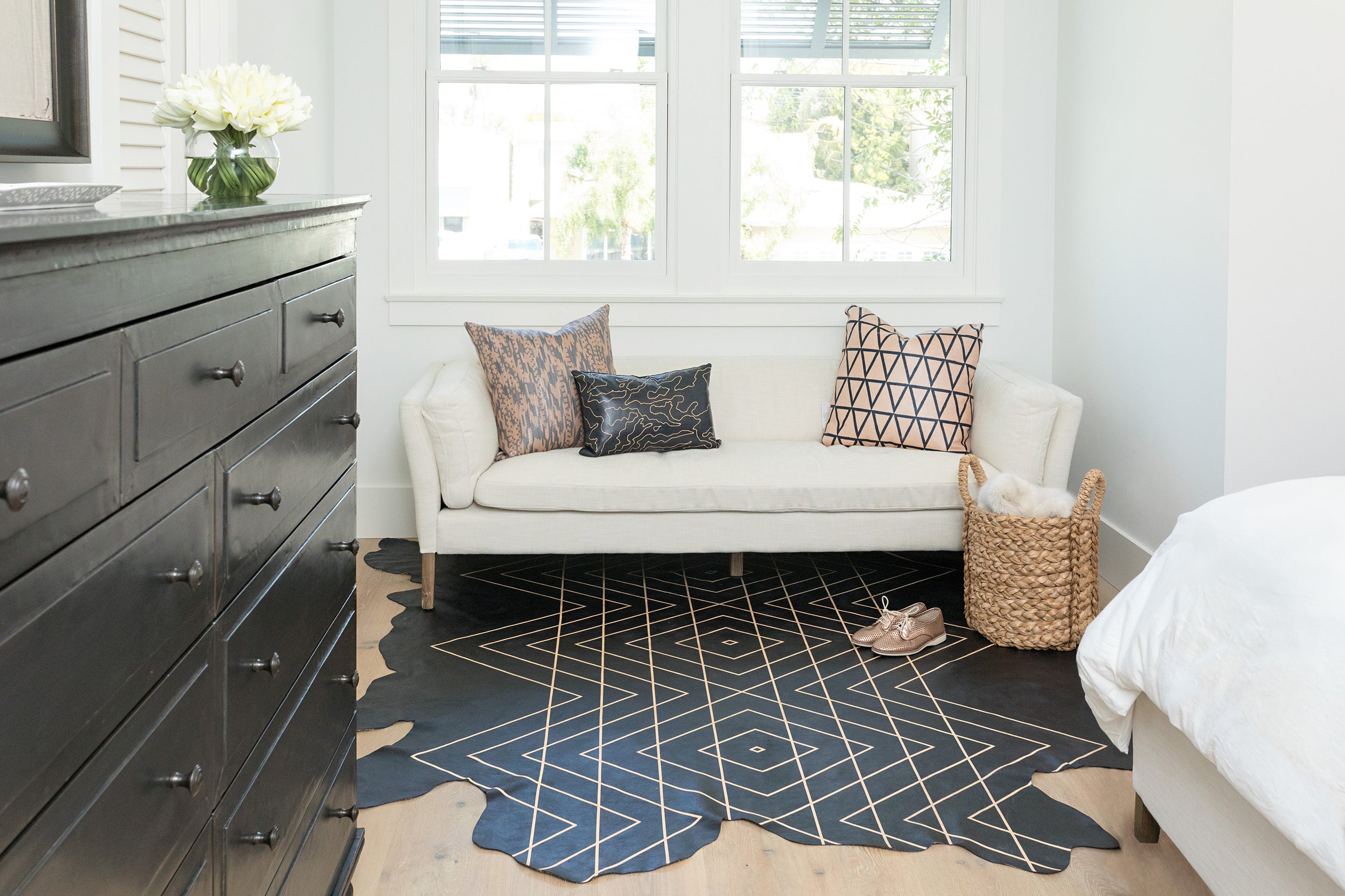 Detail of a cozy bedroom sitting area with a cowhide rug in black with a tan geometric overlay.