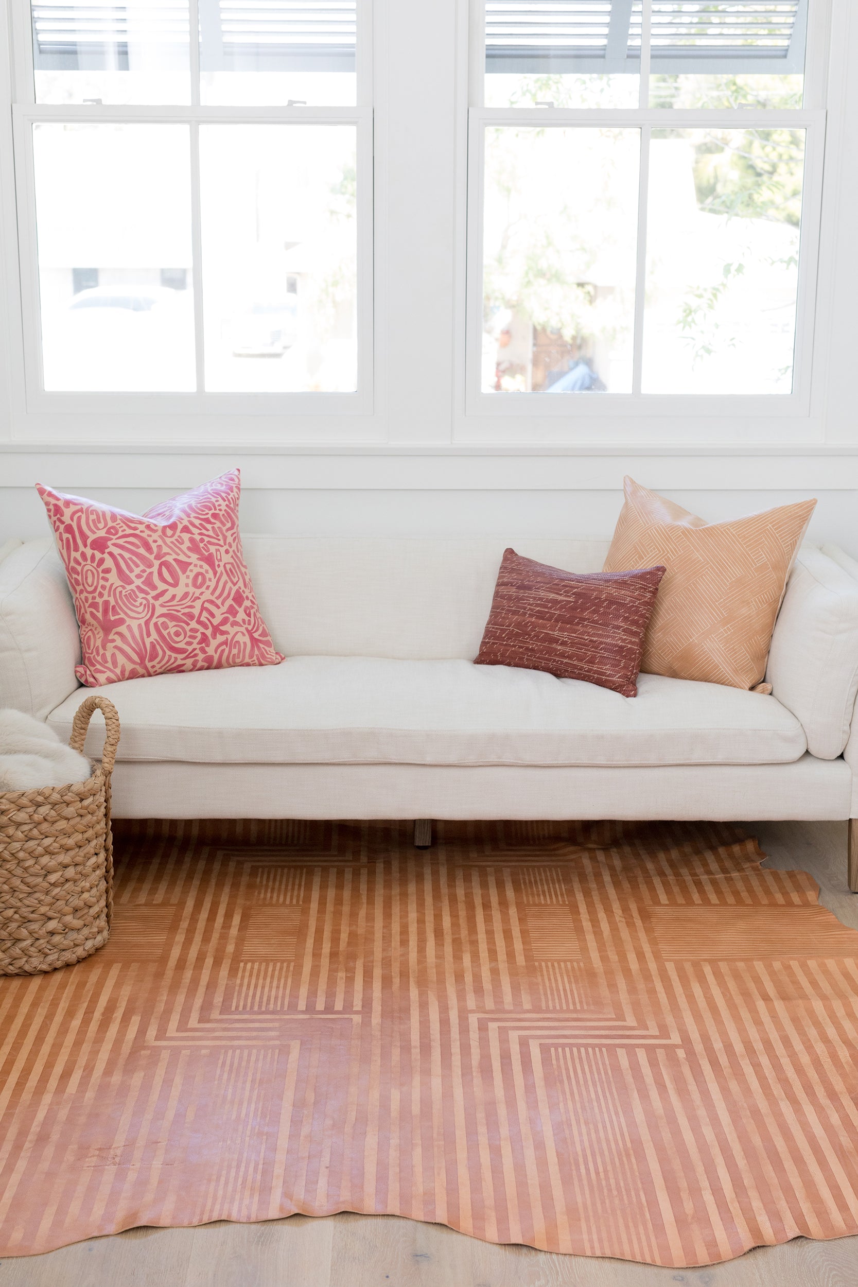 A bright living space with a large cowhide rug in tan with a geometric stripe overlay in cream.