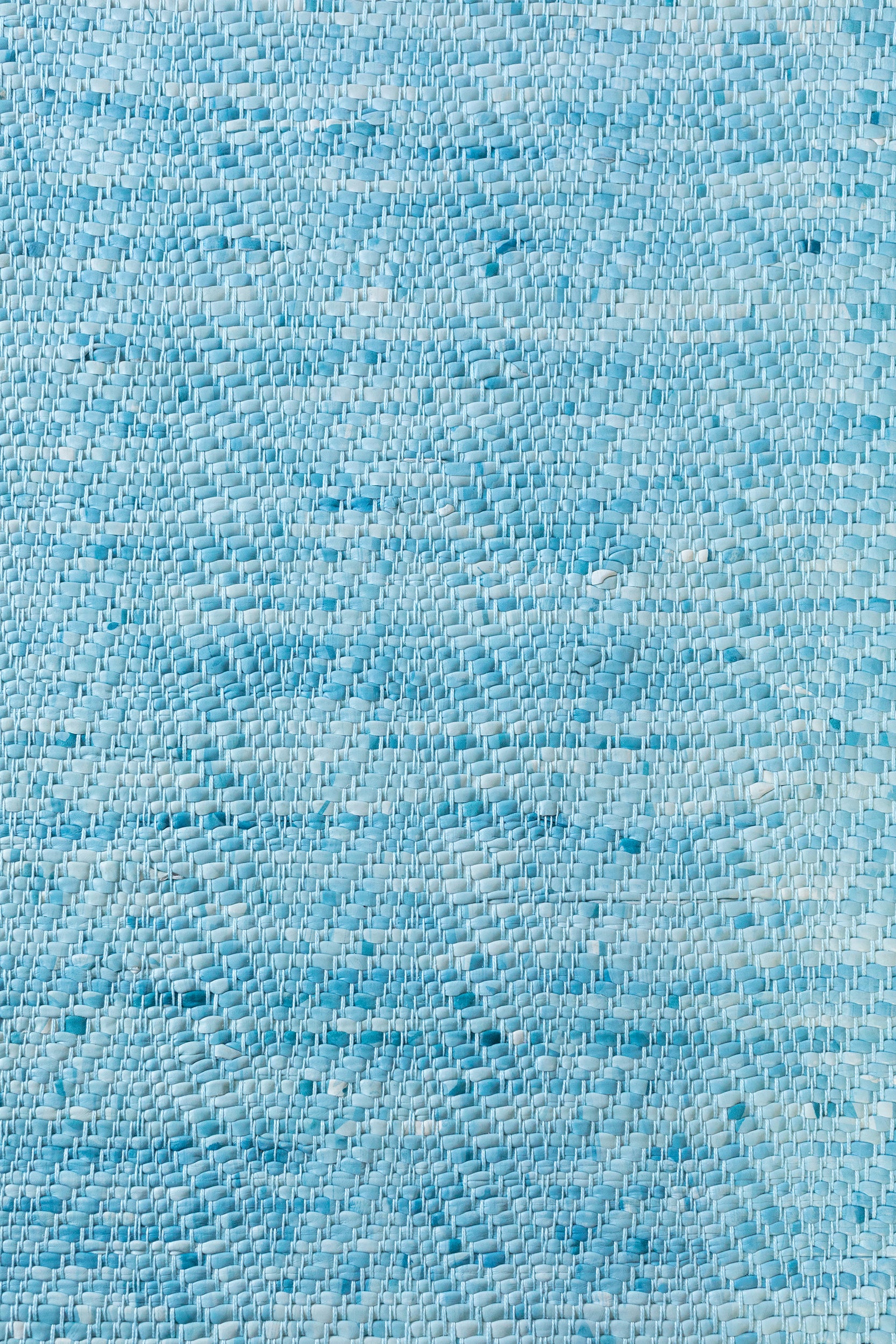 Detail of a woven leather rug in a striped wave texture in shades of turquoise with cream accents.