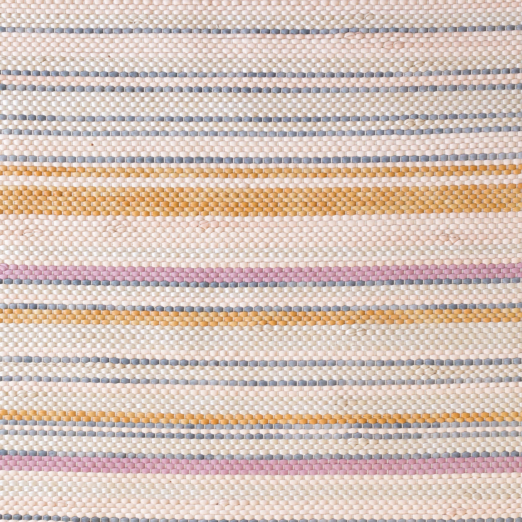 Close-up of a woven leather rug in an irregular stripe print in shades of pink, yellow and blue.