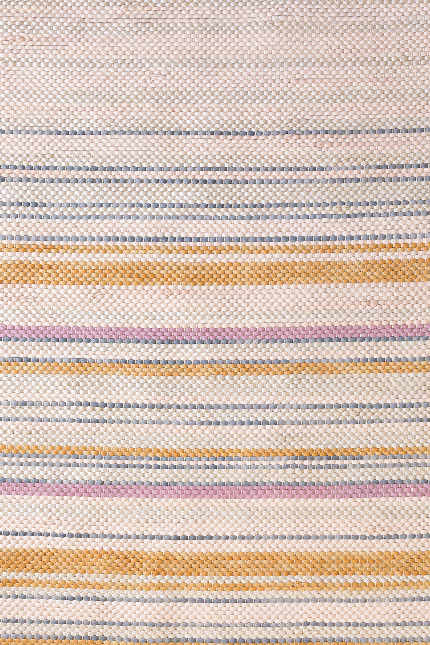 Close-up of a woven leather rug in an irregular stripe print in shades of pink, yellow and blue.