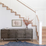 A sunny stairwell with a large cowhide rug in navy with a painterly starburst overlay in blue.