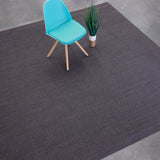 Overhead shot of a chair sitting on a woven leather rug in a herringbone pattern in mottled gray with pink accents.