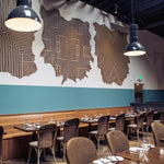 A restaurant space with cowhide wall hangings in white with geometric stripe overlays in black.