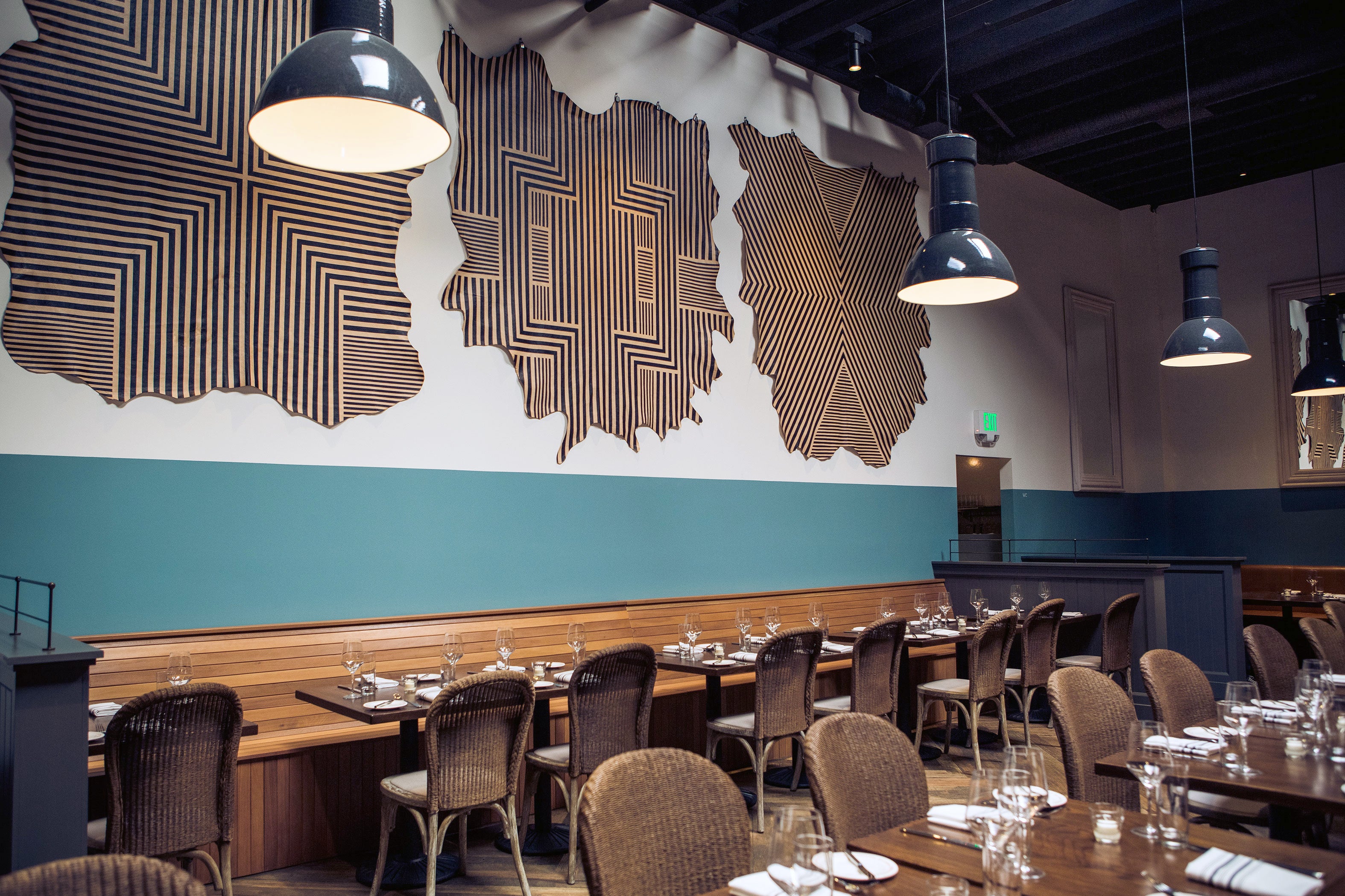 A restaurant space with cowhide wall hangings in white with geometric stripe overlays in black.