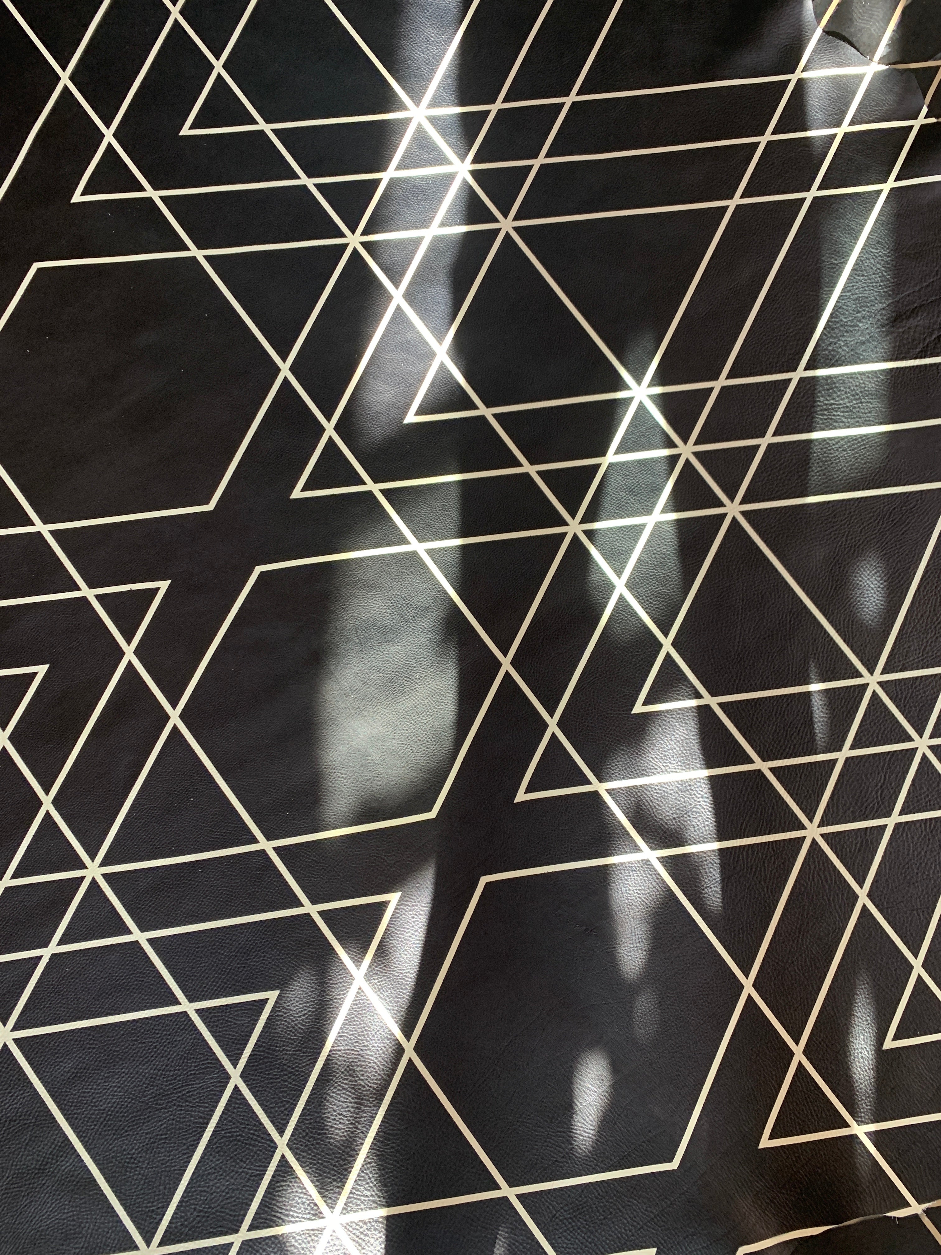 Close-up of a cowhide rug in black with a tan geometric overlay.