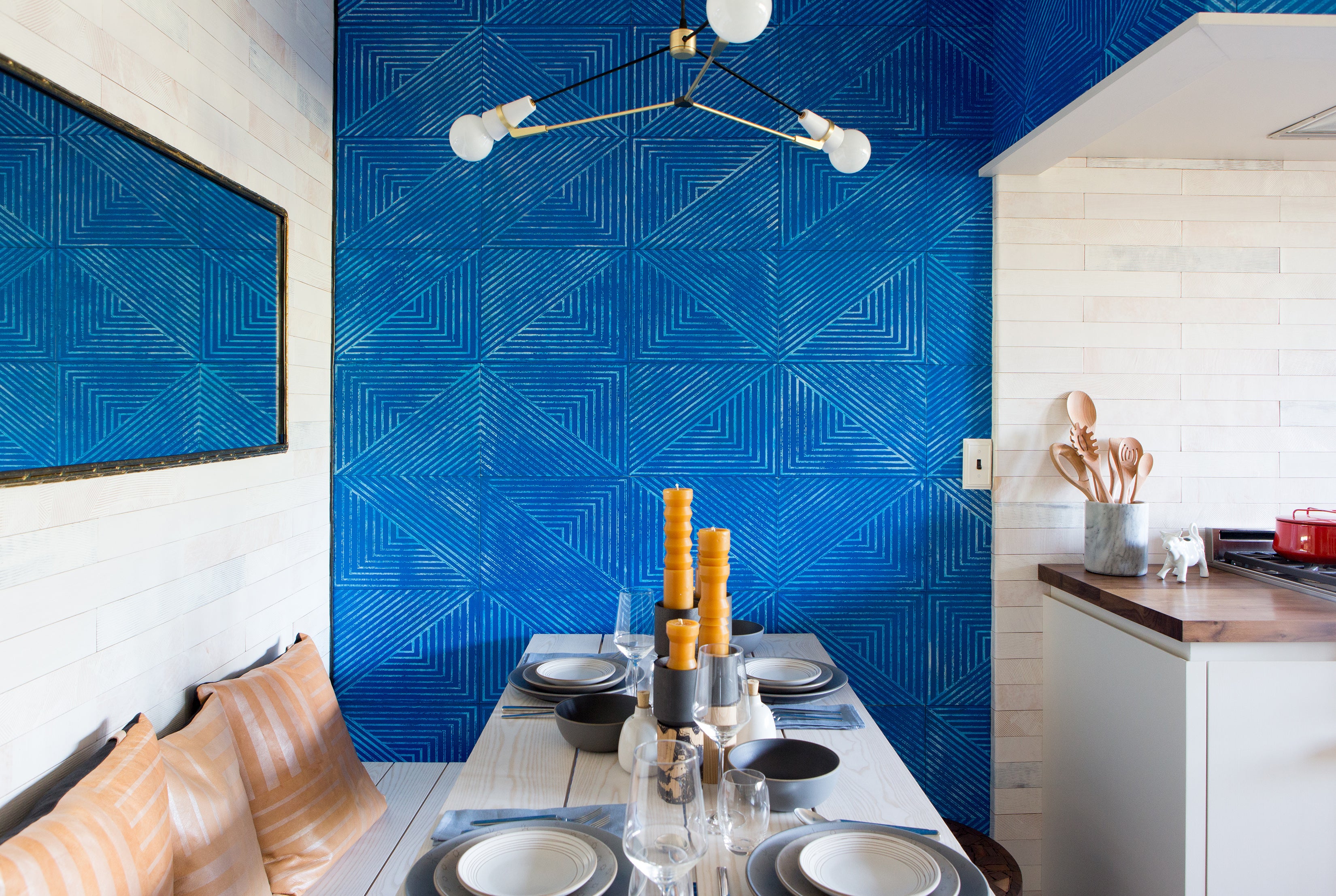 A kitchen table set with dishes against an Installation of leather wall tiles in an angular geometric pattern in blue and white.