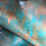 Draped upholstery leather in a textural brushstroke pattern in turquoise and gold.