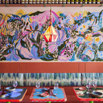 A row of colorful restaurant booths with a painted mural and cushions upholstered in painted leather.