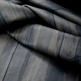 Draped upholstery leather in blue with an abstract stripe overlay in shades of navy and gray.