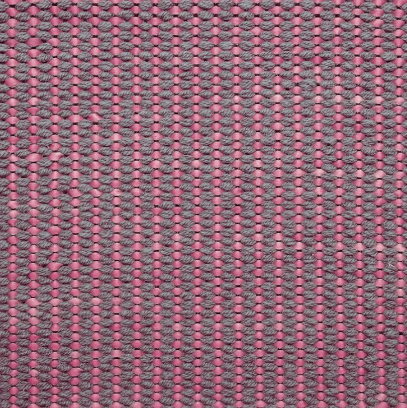 Detail of a woven leather rug in a gridded texture in gray with pink accents.