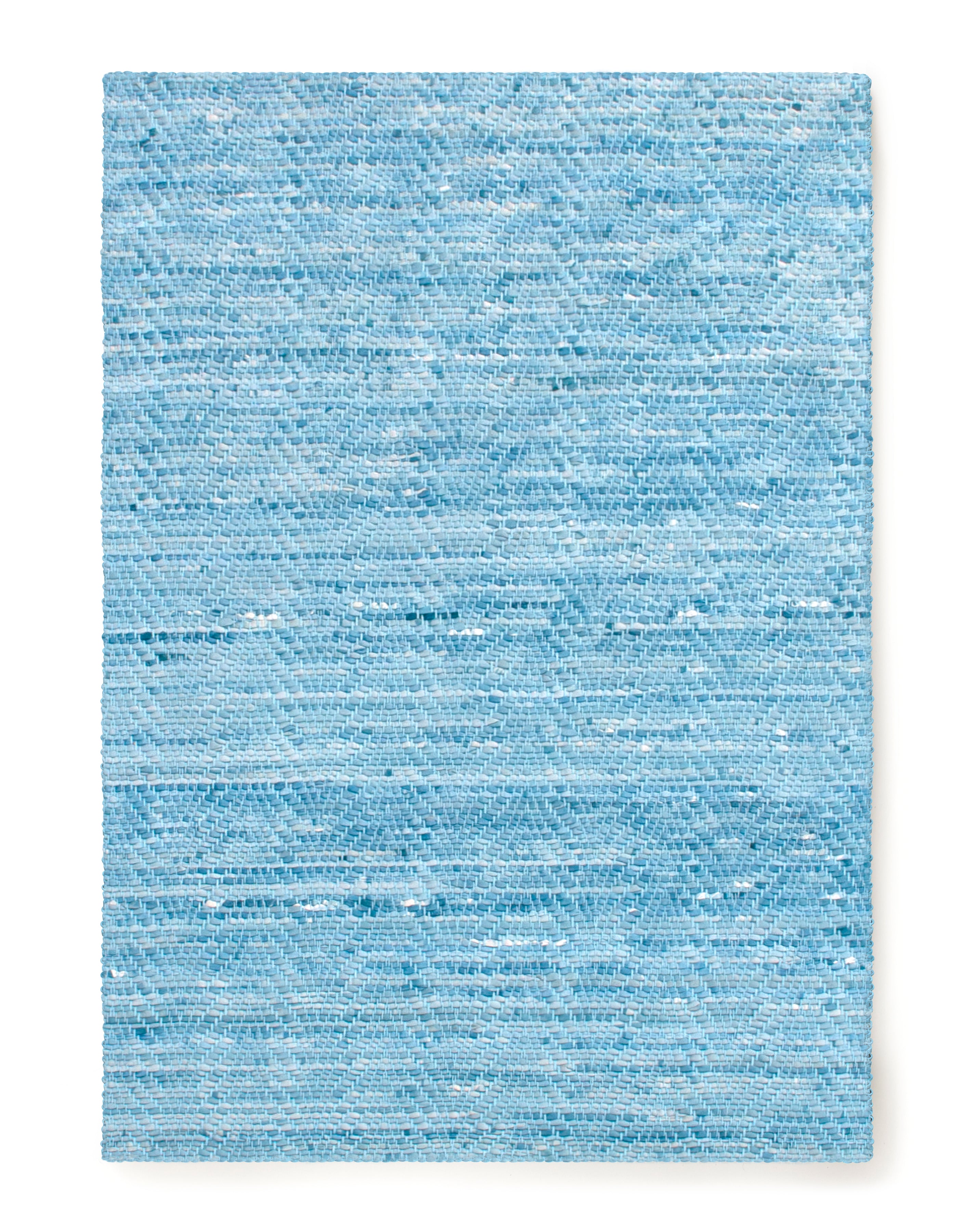 Overhead shot of a woven leather rug in a striped wave texture in shades of turquoise with cream accents.