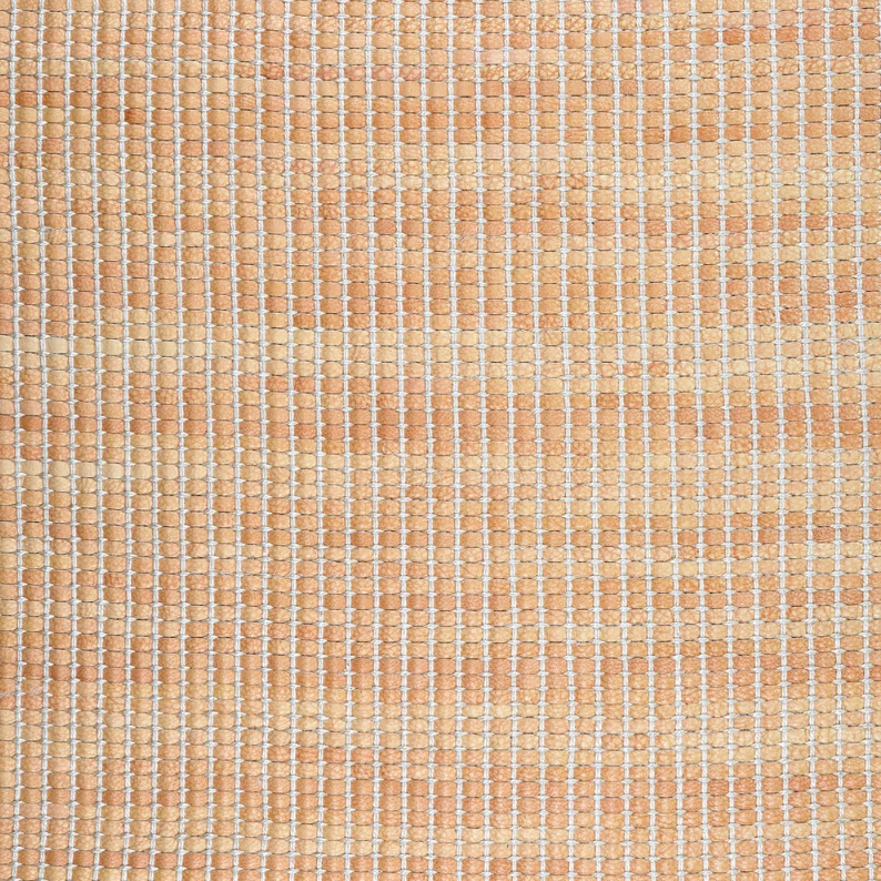 Detail of upholstery leather yardage in a grid texture in mottled orange with white accents.