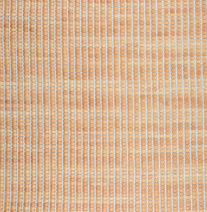 Detail of upholstery leather yardage in a grid texture in mottled orange with white accents.