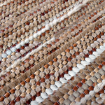 Detail of a woven leather rug in a striped grid texture in shades of brown and cream.