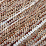 Detail of a woven leather rug in a striped grid texture in shades of brown and cream.