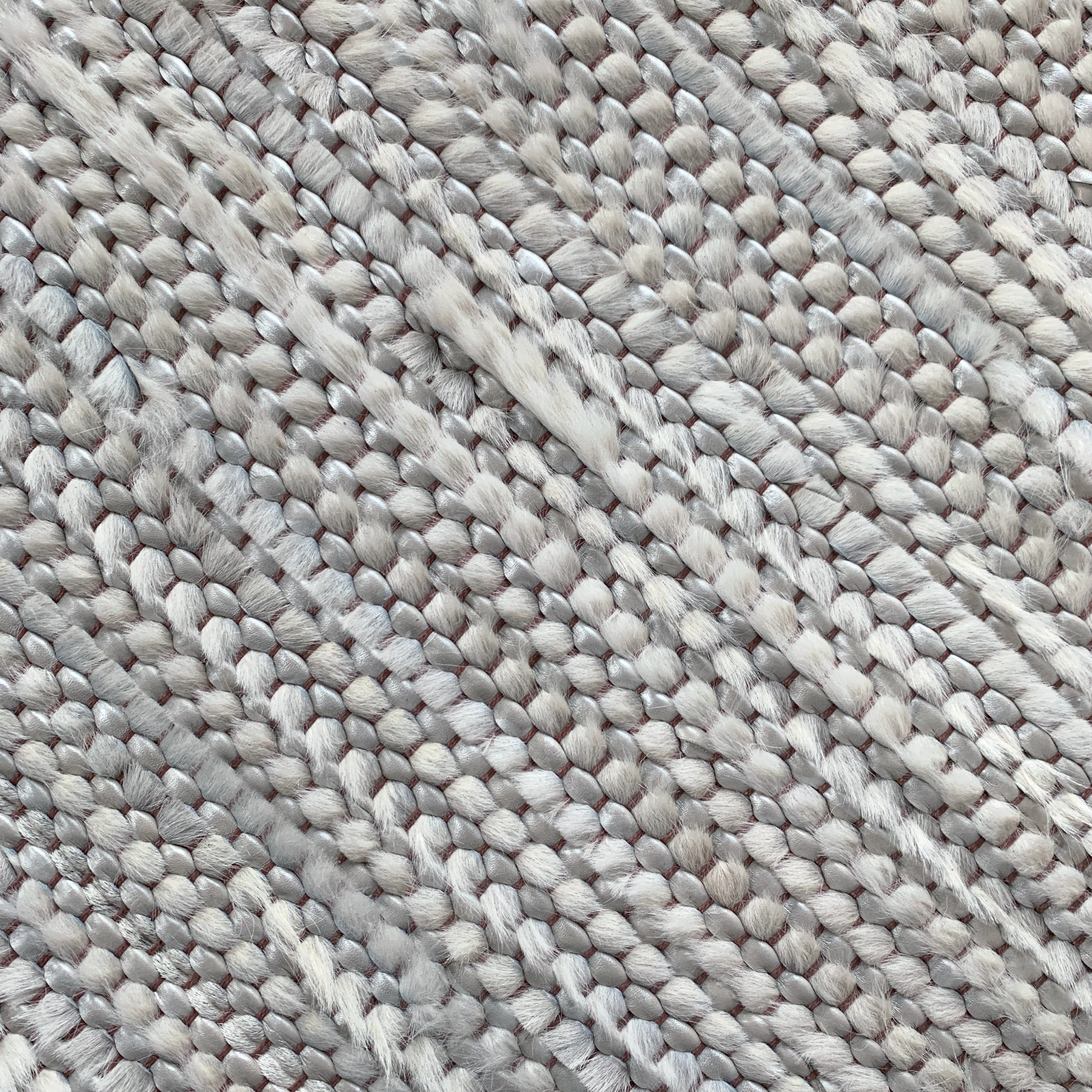 Detail of a woven leather rug in a striped grid texture in gray.