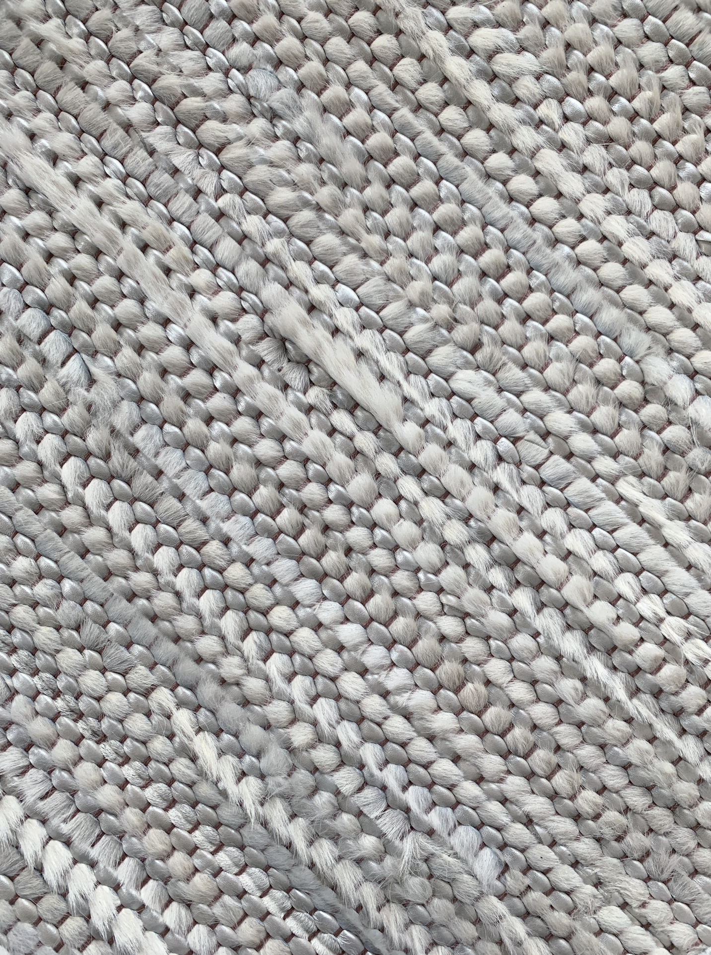 Detail of a woven leather rug in a striped grid texture in gray.