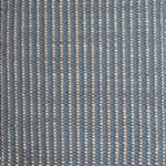 Detail of a woven leather rug in a gridded texture in blue with gray accents.