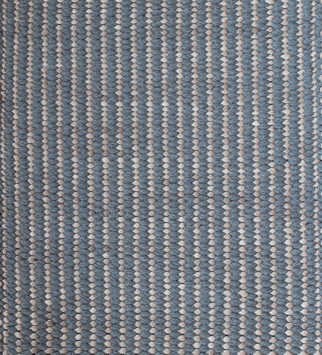 Detail of a woven leather rug in a gridded texture in blue with gray accents.