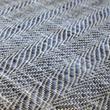 Detail of a woven leather rug in a striped wave texture in shades of blue with cream accents.