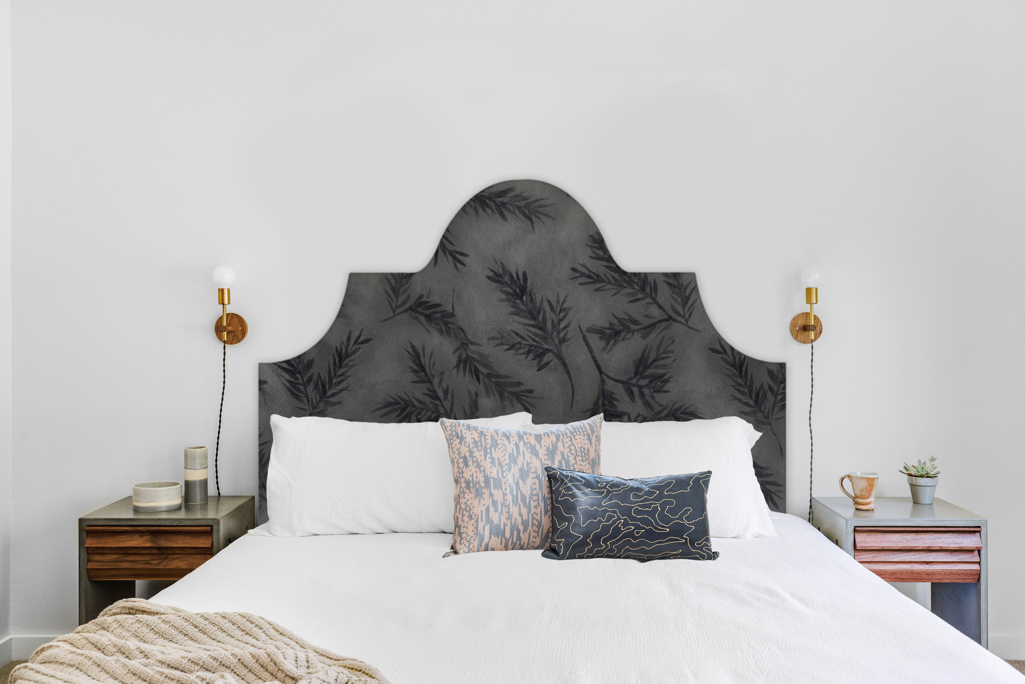 Detail of a bedroom space with a headboard upholstered in cowhide leather in gray with a black botanical overlay.