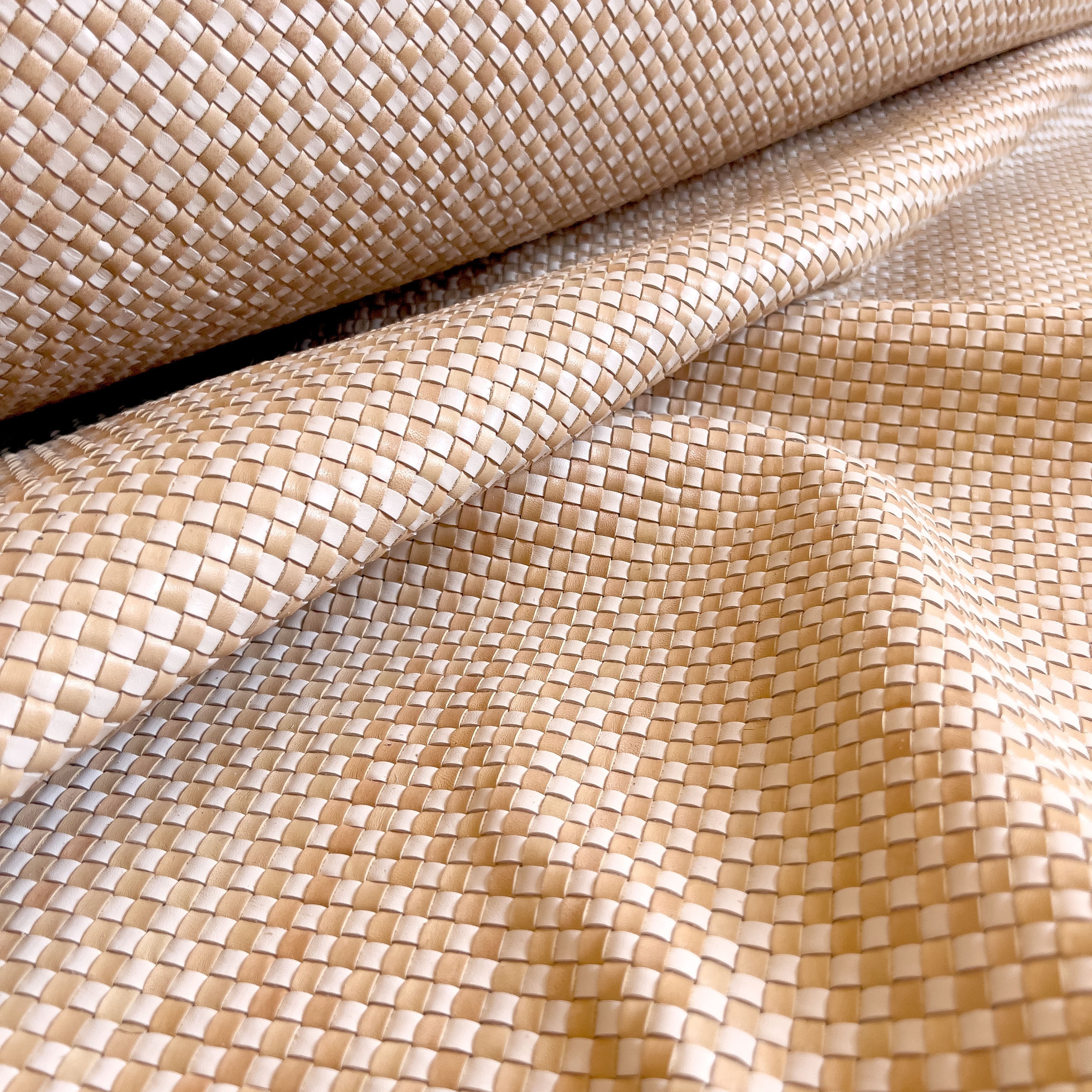 Draoed upholstery leather yardage in a woven grid in tan and white.