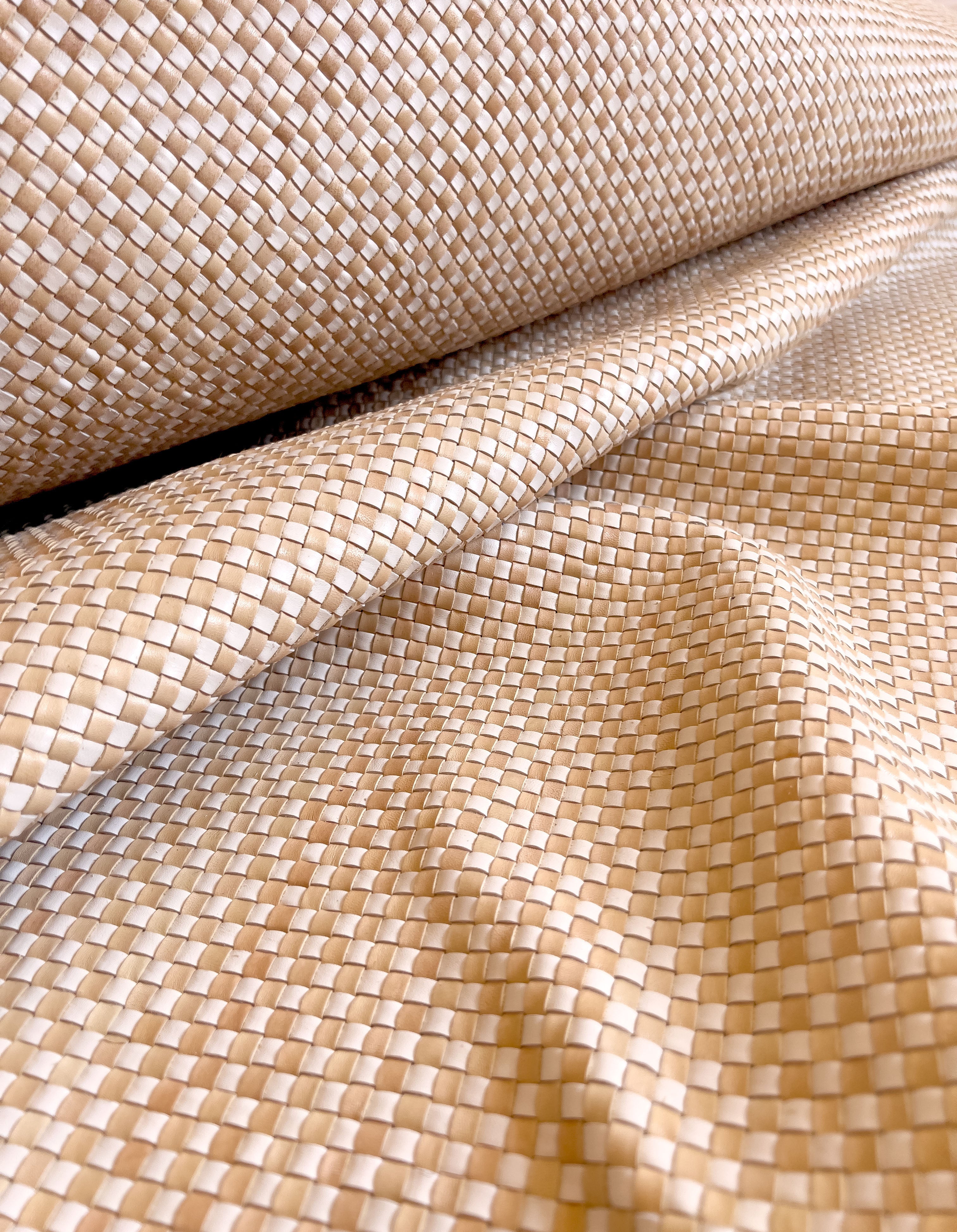 Draoed upholstery leather yardage in a woven grid in tan and white.