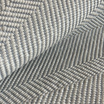 Detail of draped woven upholstery leather in a herringbone pattern in light gray.