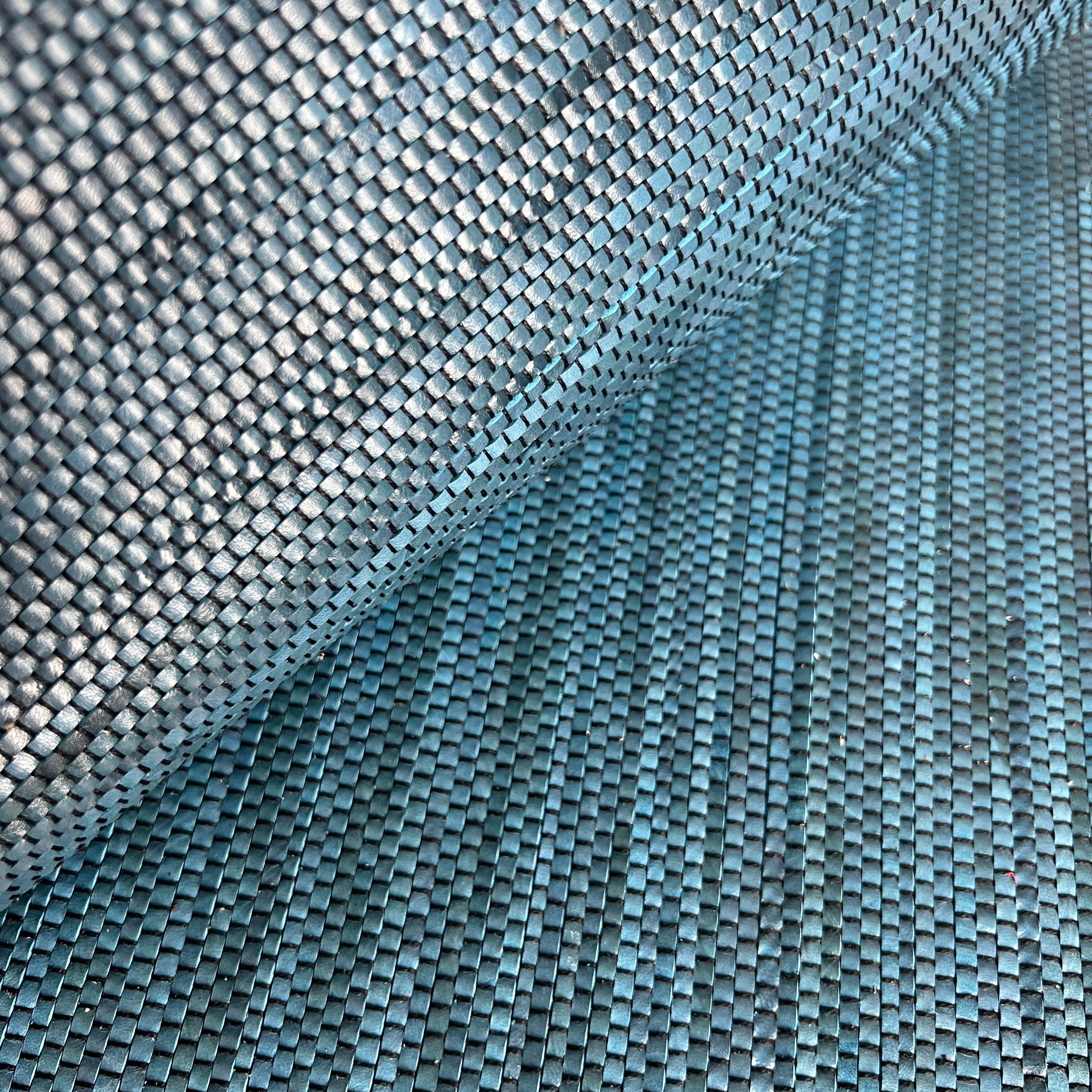 Close-up of draped upholstery leather in a tight woven texture in shades of blue.