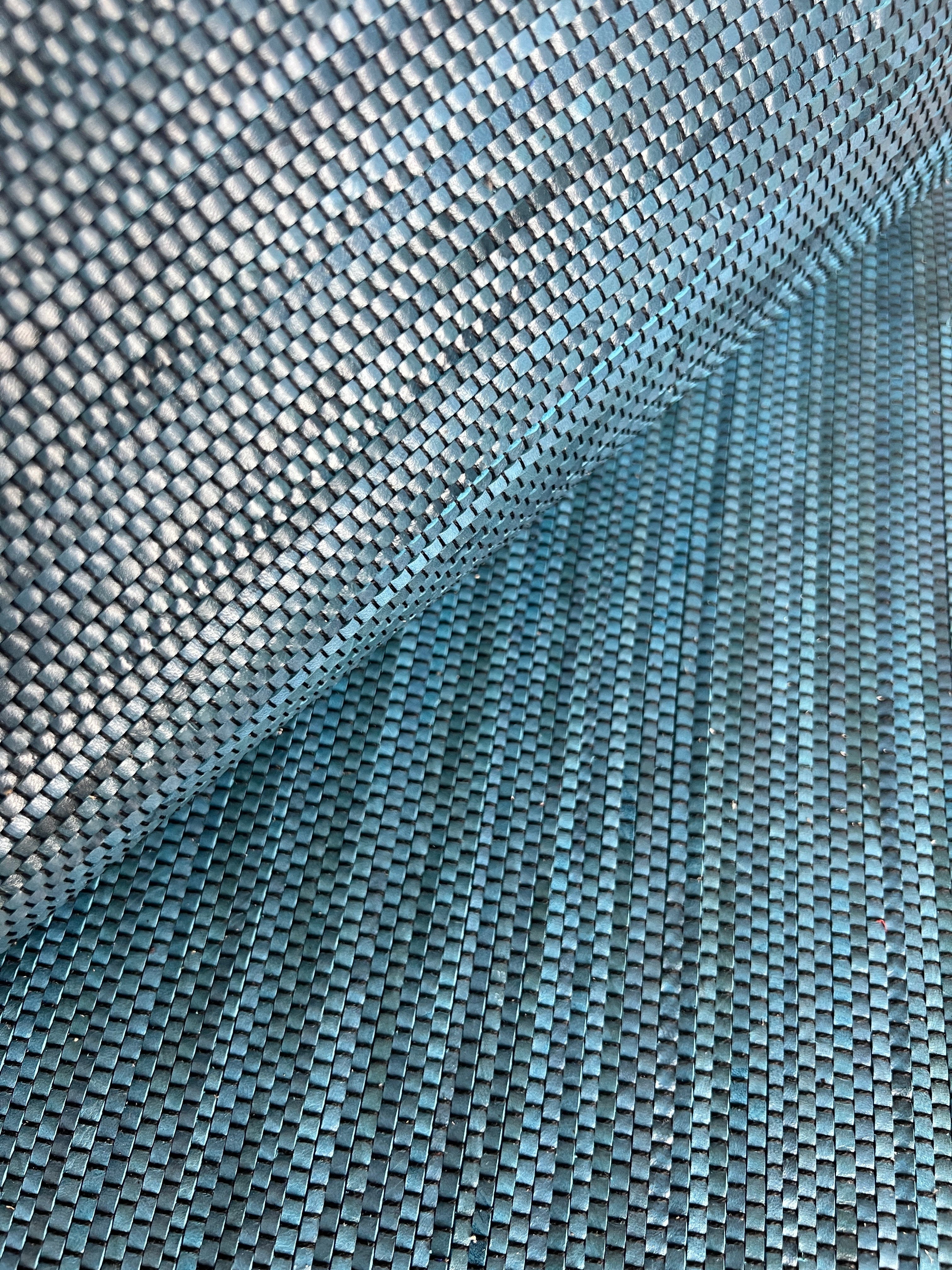 Close-up of draped upholstery leather in a tight woven texture in shades of blue.