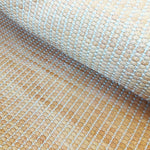 Draped upholstery leather yardage in a grid texture in mottled orange with white accents.