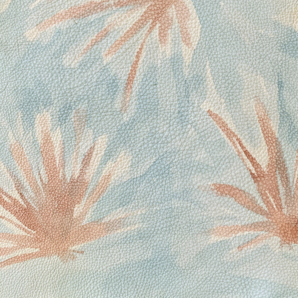 Close-up of a cowhide rug in light blue with a painterly flower print in yellow and coral.