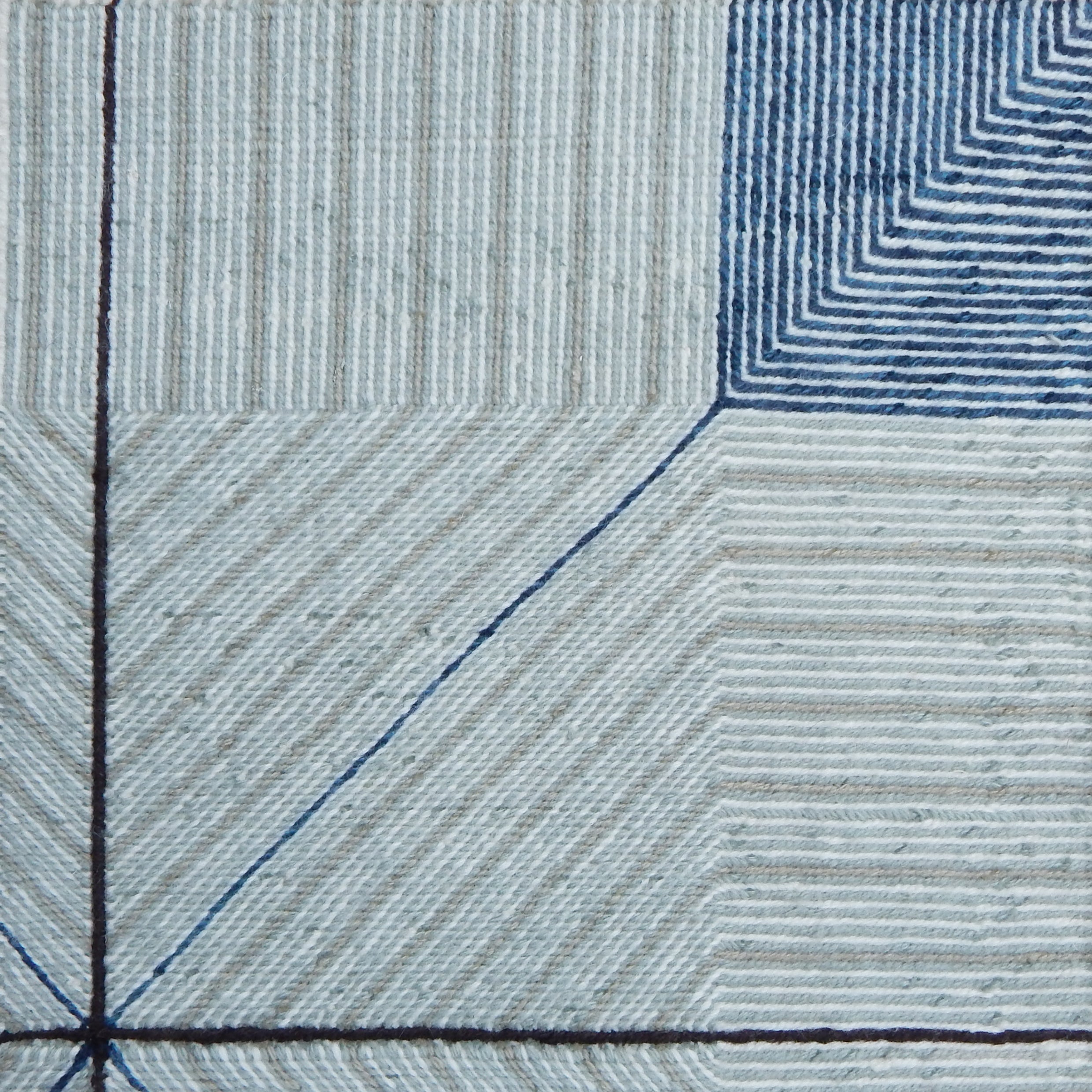 Close-up of a textured rug with blue and gray lines