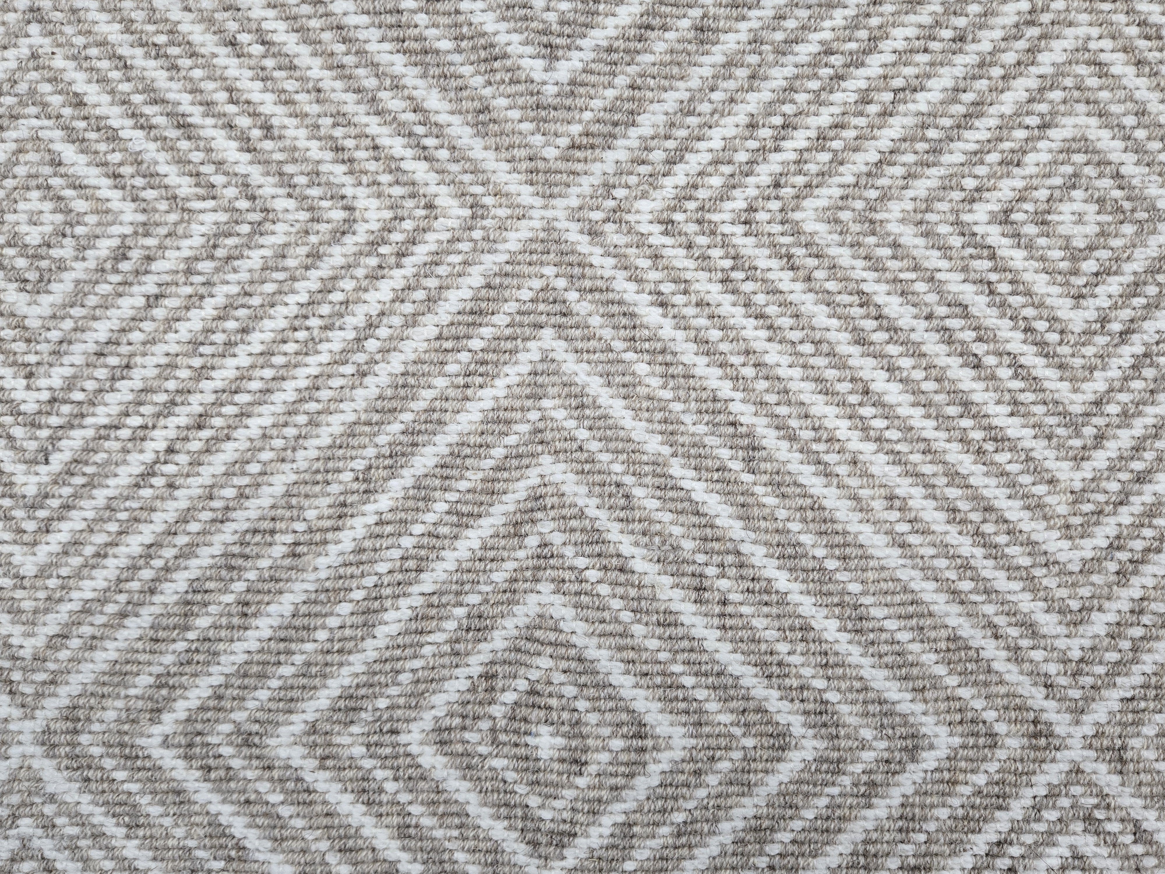 Broadloom carpet sample in a linear diamond design in white and taupe. 