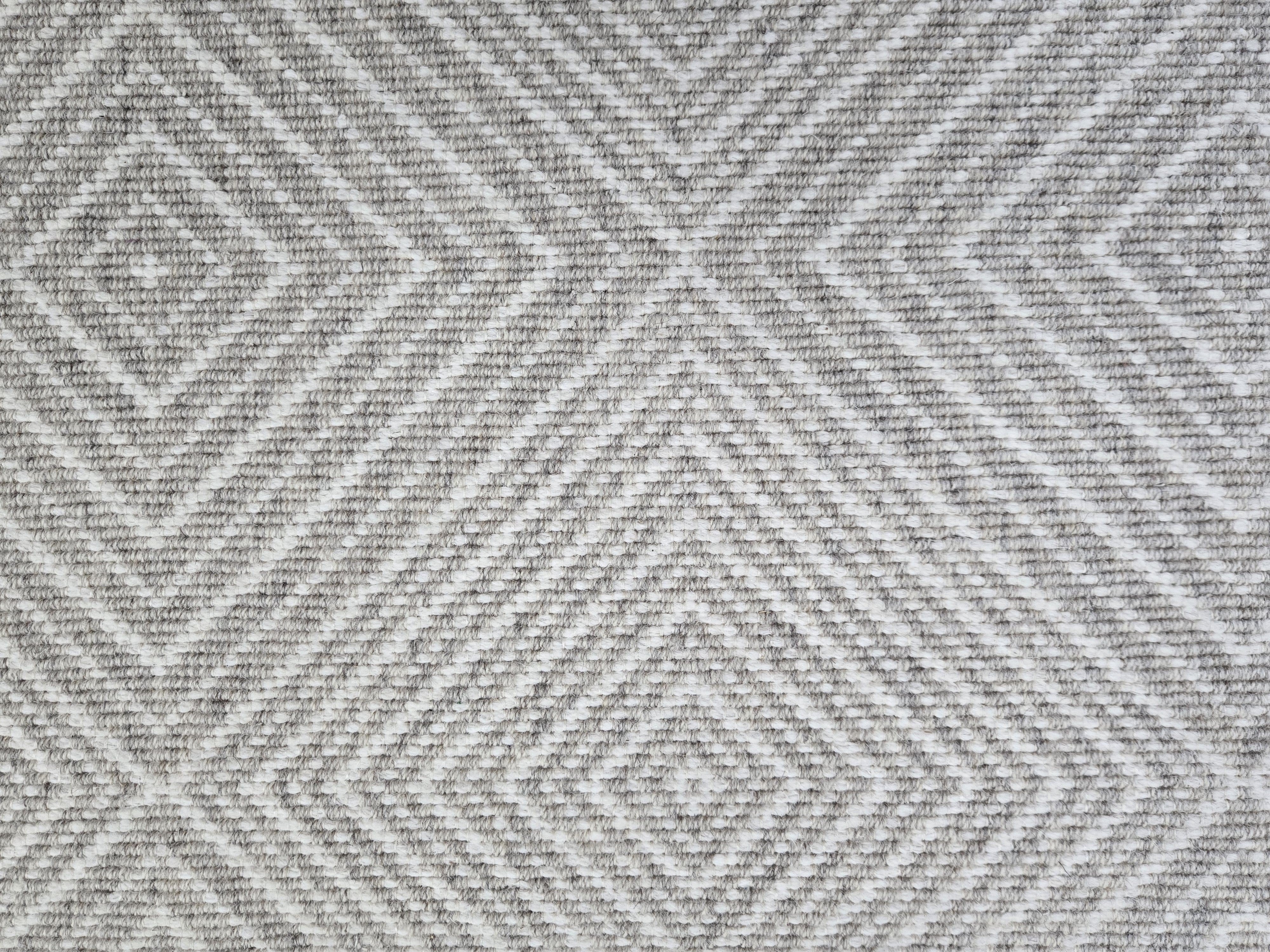 Broadloom carpet sample in a linear diamond design in white and grey.