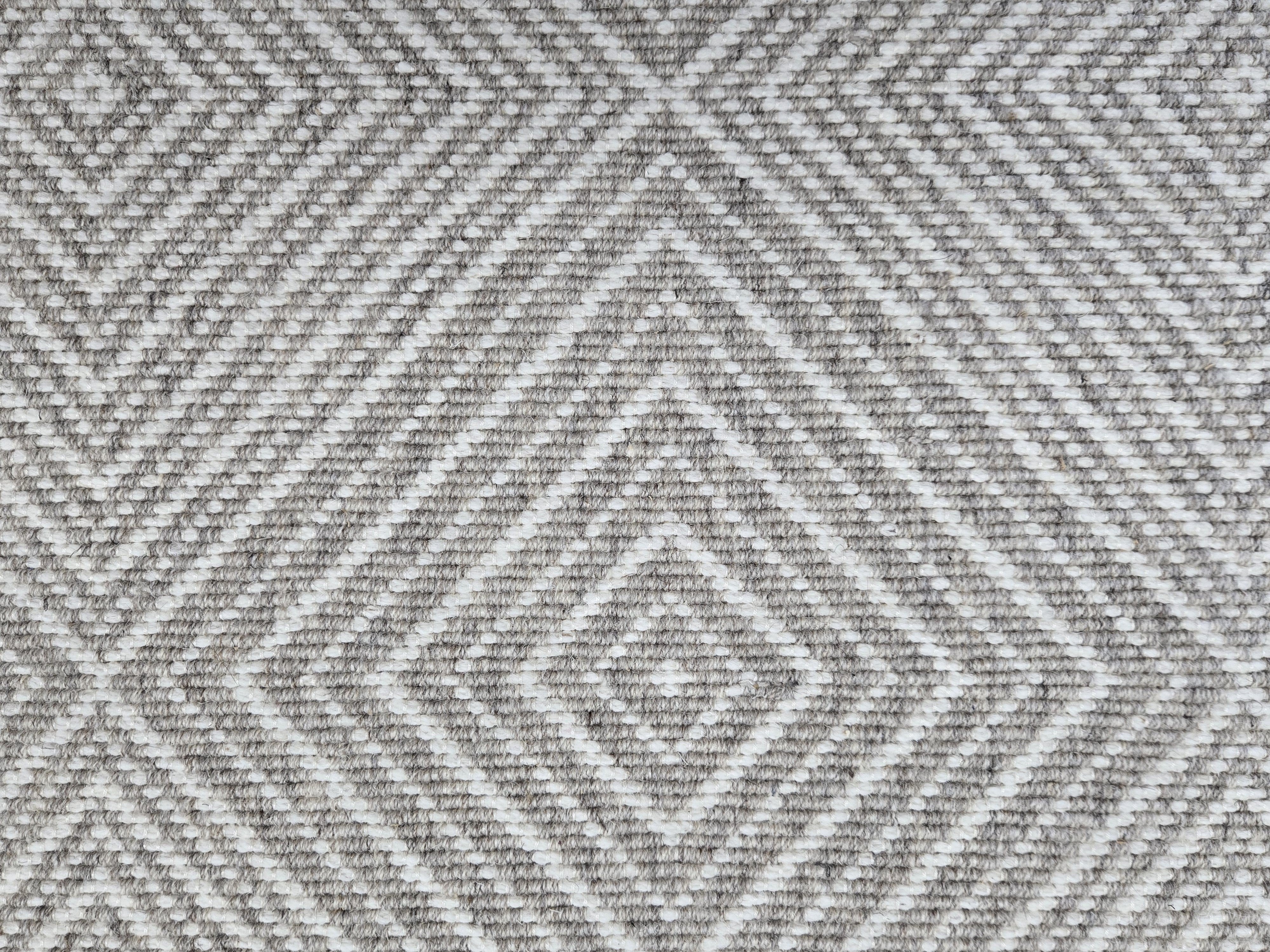 Broadloom carpet sample in a linear diamond design in white and heathered grey