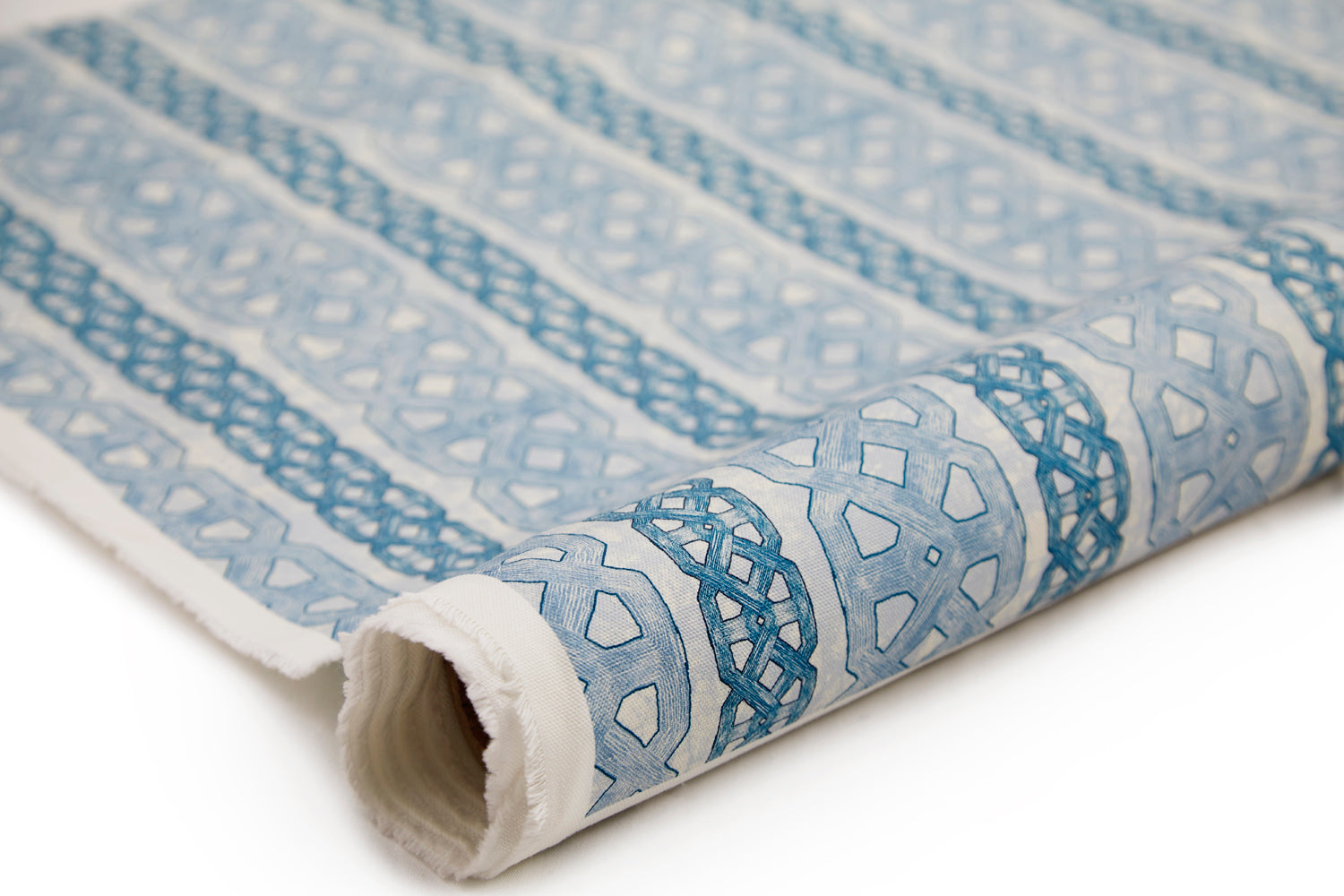 Partially unrolled fabric in a geometric stripe print in blue and navy on a mottled tan field.