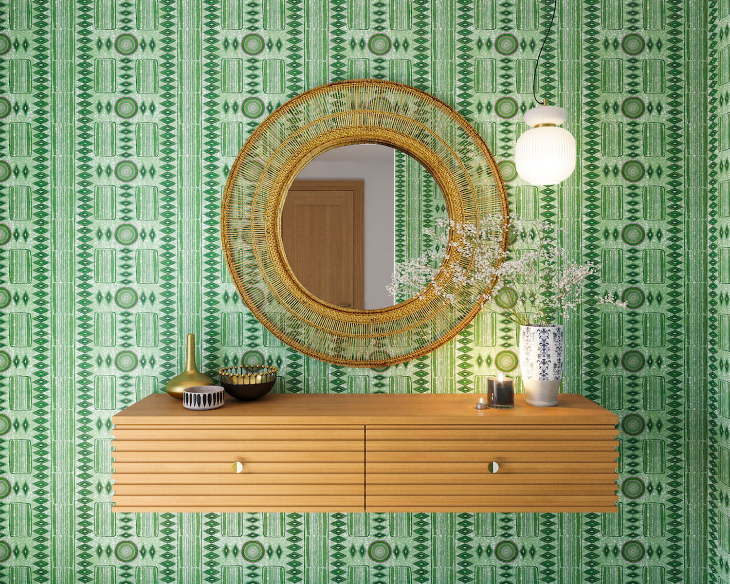 A floating shelf and statement mirror hang on a wall papered in a geometric stripe print in shades of green and purple.