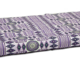 Partially unrolled fabric in a playful geometric stripe print in shades of purple with green accents.