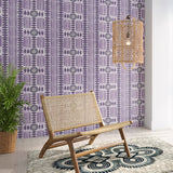 Styled living room tableau with a wall papered in a geometric stripe print in purple with green accents.